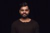 Close up portrait of young man isolated on black studio background. Photoshot of real emotions of male model. Smiling, feeling happy. Facial expression, pure and clear human emotions concept.